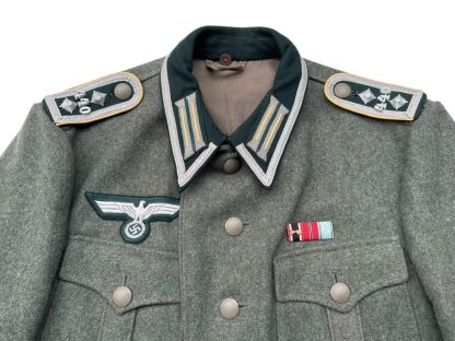 ChatGPT "Close-up image showcasing the German M36 field blouse uniform jacket, meticulously tailored with authentic details including buttoned pockets, collar tabs, and shoulder straps, representing the iconic attire worn by German soldiers during World War II. This uniform jacket embodies the historical significance of the era, evoking images of wartime mobilization, military campaigns, and the distinctive aesthetic of the German armed forces during that time."