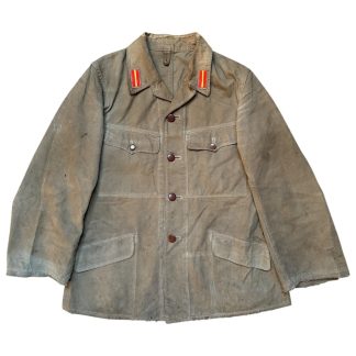 World War II Japanese Army Type 3 summer uniform jacket made of olive-brown fabric, featuring long sleeves, four front pockets with button closures, and a button-down front with dark brown buttons. The jacket has a folded collar adorned with red and yellow insignia patches, indicating rank or unit affiliation. The fabric shows signs of wear and discoloration, consistent with its age and use.