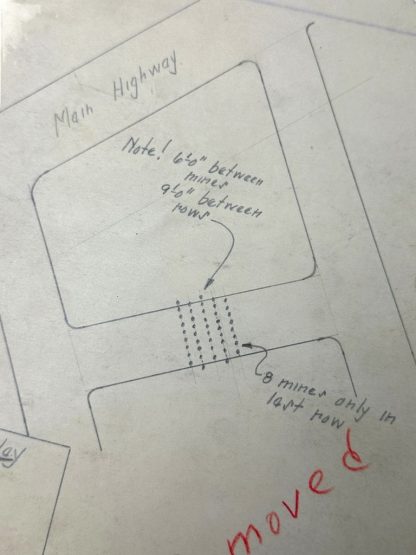 Mappa schematica segreta americana di un campo minato, disegnata il 24 dicembre 1944 a Baugnez durante l'Offensiva delle Ardenne. La mappa include annotazioni scritte a mano, come le distanze tra le mine, una strada principale ('Main Highway') e una panoramica della disposizione del campo minato. Con precisione militare, vengono dettagliate le coordinate e le specifiche, come le dimensioni e la collocazione delle mine. La parola 'Removed' è evidenziata in rosso sul documento. Questo artefatto storico offre una visione della pianificazione strategica durante la Seconda Guerra Mondiale.