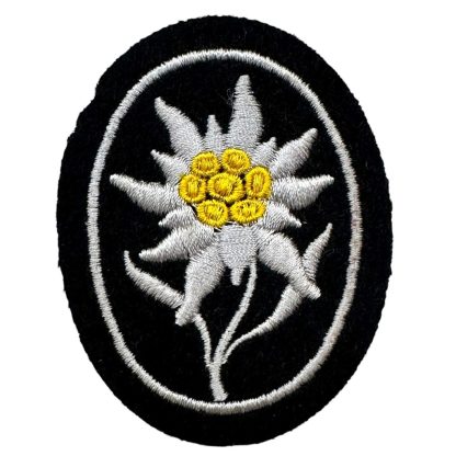 WWII German Waffen-SS Gebirgsjäger insignia featuring an embroidered Edelweiss flower with white petals, a yellow center, and a black oval background, symbolizing mountain troops.