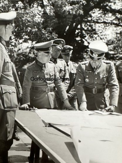 Erwin Rommel inspecting the battle plan at the Normandy coast in 1944. He is inspecting several maps with his officers.