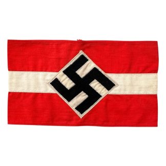 A historical Hitler Youth armband from World War II, made of red cotton with a white central section featuring a black swastika inside a circle.