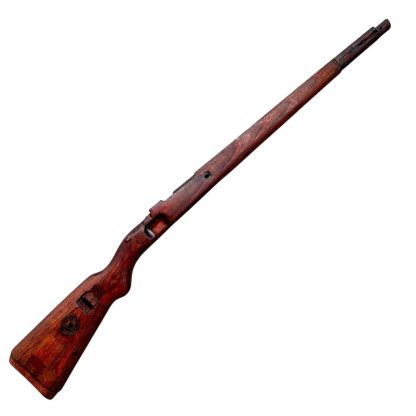 German WWII Mauser K98 wooden rifle stock, showcasing a rich reddish-brown wood finish with visible wear and aging, featuring the characteristic design for a bolt-action rifle. The stock includes a cutout for the bolt mechanism and a recess for the magazine well, highlighting its historical craftsmanship.