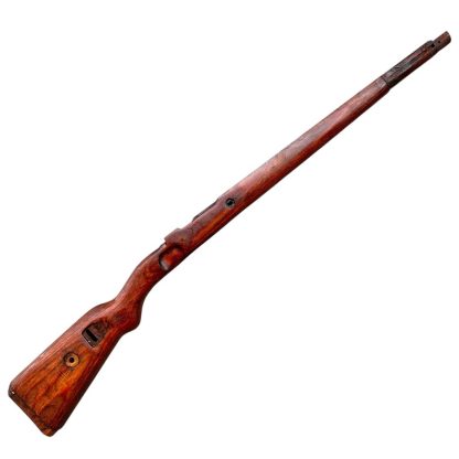 A vintage wooden rifle stock for a German WWII Mauser K98, showcasing a polished reddish-brown finish with visible wood grain texture. The design features a curved grip and cutouts for mounting hardware. The stock appears well-preserved with signs of age and use, such as minor scuffs and wear, adding to its historical authenticity.