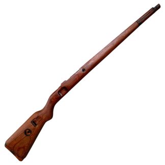 A vintage wooden rifle stock for a German WWII Mauser K98, showcasing a polished reddish-brown finish with visible wood grain texture. The design features a curved grip and cutouts for mounting hardware. The stock appears well-preserved with signs of age and use, such as minor scuffs and wear, adding to its historical authenticity.