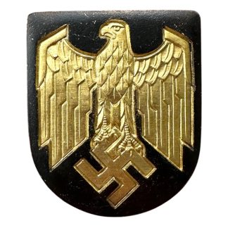 This shield was worn on the German Kriegsmarine tropical pith helmet during World War II. It is metal shield with a golden eagle and black background on it.