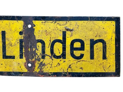 A weathered yellow metal German traffic sign from World War II with an arrow-shaped design, black border, and the text 'nach Linden' in black letters, showing clear signs of age and damage.