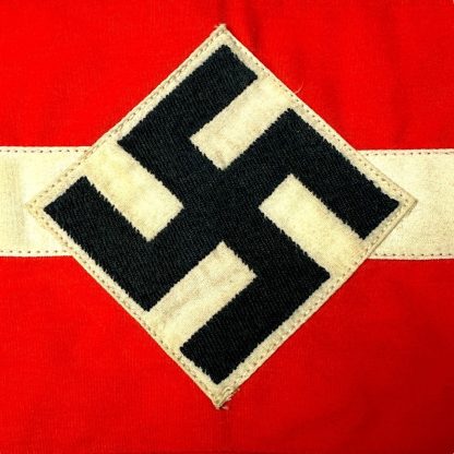 Original Hitler Youth armband from World War II, red with a white band and a black swastika in a diamond-shaped design, preserved in historical condition.