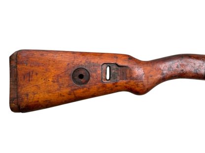 Image d'une crosse en bois allemande de fusil Mauser K98 de la Seconde Guerre mondiale, avec une finition brun foncé patinée et des découpes visibles pour fixer le mécanisme du fusil.