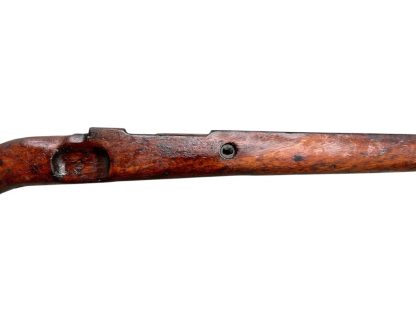 Image d'une crosse en bois allemande de fusil Mauser K98 de la Seconde Guerre mondiale, avec une finition brun foncé patinée et des découpes visibles pour fixer le mécanisme du fusil.