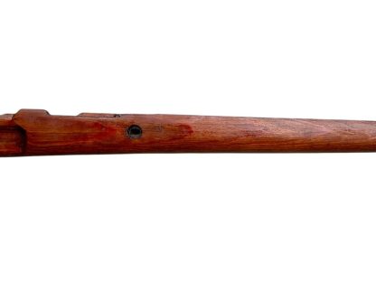 A vintage wooden rifle stock for a German WWII Mauser K98, showcasing a polished reddish-brown finish with visible wood grain texture. The design features a curved grip and cutouts for mounting hardware. The stock appears well-preserved with signs of age and use, such as minor scuffs and wear, adding to its historical authenticity.