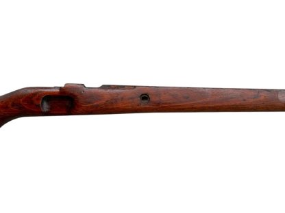 German WWII Mauser K98 wooden rifle stock, showcasing a rich reddish-brown finish, with visible wear and patina from age and use. The stock includes a cutout for the bolt handle and features slots for a sling, along with a detailed grain pattern typical of wartime production.