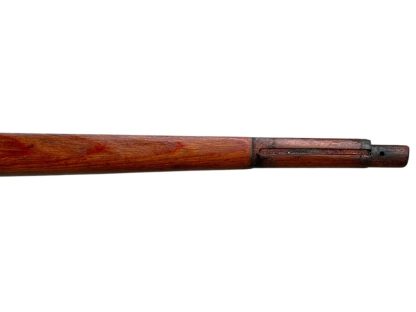 A vintage wooden rifle stock for a German WWII Mauser K98, showcasing a polished reddish-brown finish with visible wood grain texture. The design features a curved grip and cutouts for mounting hardware. The stock appears well-preserved with signs of age and use, such as minor scuffs and wear, adding to its historical authenticity.