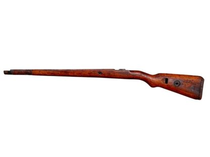 Image d'une crosse en bois allemande de fusil Mauser K98 de la Seconde Guerre mondiale, avec une finition brun foncé patinée et des découpes visibles pour fixer le mécanisme du fusil.