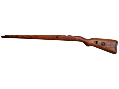 A vintage wooden rifle stock for a German WWII Mauser K98, showcasing a polished reddish-brown finish with visible wood grain texture. The design features a curved grip and cutouts for mounting hardware. The stock appears well-preserved with signs of age and use, such as minor scuffs and wear, adding to its historical authenticity.