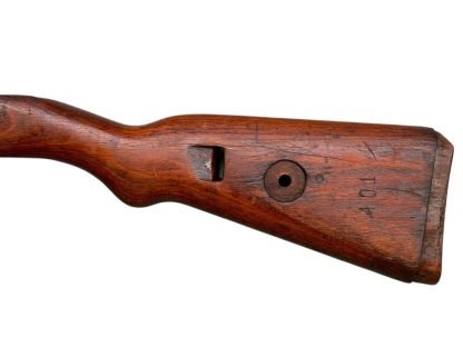 German WWII Mauser K98 wooden rifle stock, showcasing a rich reddish-brown finish, with visible wear and patina from age and use. The stock includes a cutout for the bolt handle and features slots for a sling, along with a detailed grain pattern typical of wartime production.