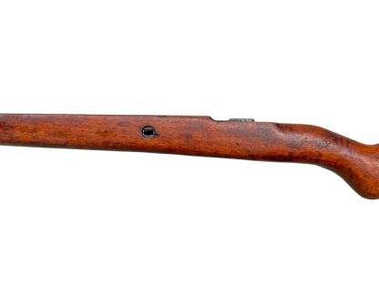 Image d'une crosse en bois allemande de fusil Mauser K98 de la Seconde Guerre mondiale, avec une finition brun foncé patinée et des découpes visibles pour fixer le mécanisme du fusil.