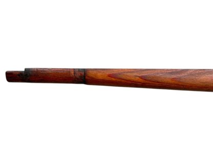 A vintage wooden rifle stock for a German WWII Mauser K98, showcasing a polished reddish-brown finish with visible wood grain texture. The design features a curved grip and cutouts for mounting hardware. The stock appears well-preserved with signs of age and use, such as minor scuffs and wear, adding to its historical authenticity.