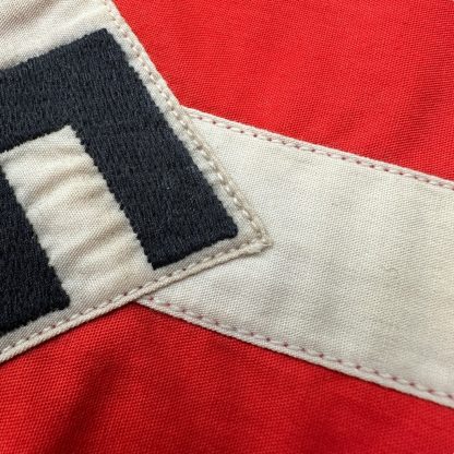 A historical Hitler Youth armband from World War II, made of red cotton with a white central section featuring a black swastika inside a circle.