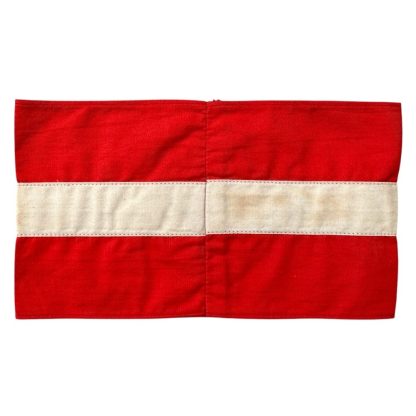 A historical Hitler Youth armband from World War II, made of red cotton with a white central section featuring a black swastika inside a circle.