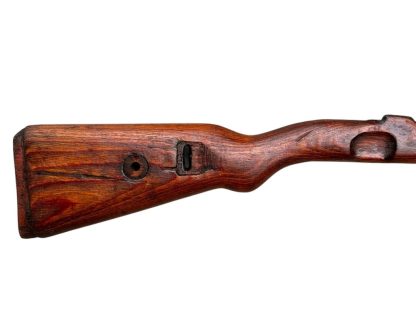 Immagine di un calcio in legno del fucile tedesco Mauser K98 della Seconda Guerra Mondiale, con una finitura marrone scuro e usurata e intagli visibili per il montaggio del meccanismo del fucile.