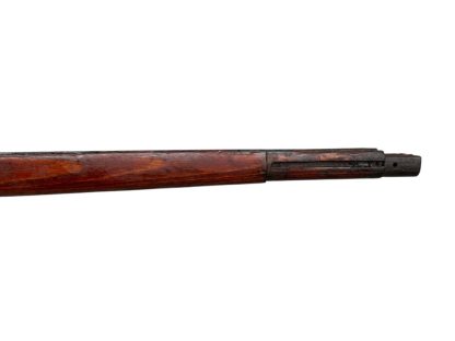 German WWII Mauser K98 wooden rifle stock, showcasing a rich reddish-brown finish, with visible wear and patina from age and use. The stock includes a cutout for the bolt handle and features slots for a sling, along with a detailed grain pattern typical of wartime production.