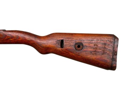 Immagine di un calcio in legno del fucile tedesco Mauser K98 della Seconda Guerra Mondiale, con una finitura marrone scuro e usurata e intagli visibili per il montaggio del meccanismo del fucile.