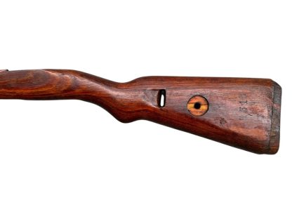 German WWII Mauser K98 wooden rifle stock, showcasing a rich reddish-brown finish, with visible wear and patina from age and use. The stock includes a cutout for the bolt handle and features slots for a sling, along with a detailed grain pattern typical of wartime production.