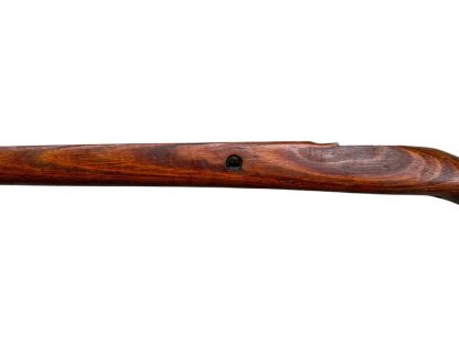 German WWII Mauser K98 wooden rifle stock, showcasing a rich reddish-brown finish, with visible wear and patina from age and use. The stock includes a cutout for the bolt handle and features slots for a sling, along with a detailed grain pattern typical of wartime production.