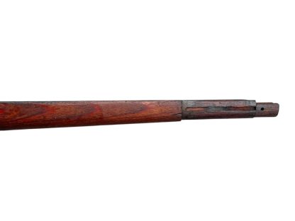 German WWII Mauser K98 wooden rifle stock, showcasing a rich reddish-brown wood finish with visible wear and aging, featuring the characteristic design for a bolt-action rifle. The stock includes a cutout for the bolt mechanism and a recess for the magazine well, highlighting its historical craftsmanship.