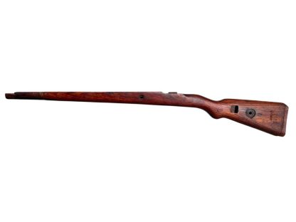 German WWII Mauser K98 wooden rifle stock, showcasing a rich reddish-brown wood finish with visible wear and aging, featuring the characteristic design for a bolt-action rifle. The stock includes a cutout for the bolt mechanism and a recess for the magazine well, highlighting its historical craftsmanship.