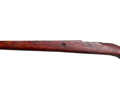 German WWII Mauser K98 wooden rifle stock, showcasing a rich reddish-brown wood finish with visible wear and aging, featuring the characteristic design for a bolt-action rifle. The stock includes a cutout for the bolt mechanism and a recess for the magazine well, highlighting its historical craftsmanship.