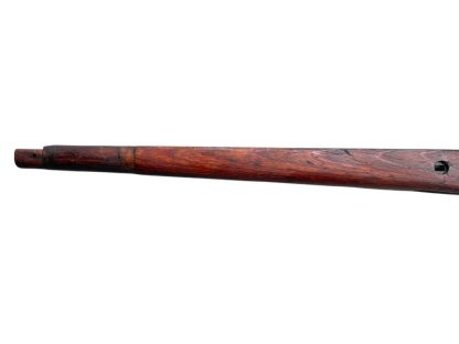 German WWII Mauser K98 wooden rifle stock, showcasing a rich reddish-brown wood finish with visible wear and aging, featuring the characteristic design for a bolt-action rifle. The stock includes a cutout for the bolt mechanism and a recess for the magazine well, highlighting its historical craftsmanship.