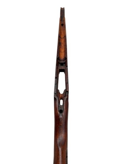 German WWII Mauser K98 wooden rifle stock, showcasing a rich reddish-brown wood finish with visible wear and aging, featuring the characteristic design for a bolt-action rifle. The stock includes a cutout for the bolt mechanism and a recess for the magazine well, highlighting its historical craftsmanship.