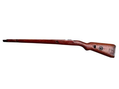 German WWII Mauser K98 wooden rifle stock, showcasing a rich reddish-brown wood finish with visible wear and aging, featuring the characteristic design for a bolt-action rifle. The stock includes a cutout for the bolt mechanism and a recess for the magazine well, highlighting its historical craftsmanship.