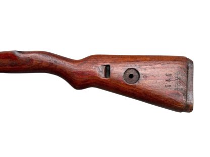 German WWII Mauser K98 wooden rifle stock, showcasing a rich reddish-brown wood finish with visible wear and aging, featuring the characteristic design for a bolt-action rifle. The stock includes a cutout for the bolt mechanism and a recess for the magazine well, highlighting its historical craftsmanship.