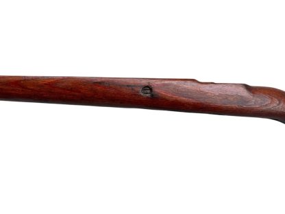 German WWII Mauser K98 wooden rifle stock, showcasing a rich reddish-brown wood finish with visible wear and aging, featuring the characteristic design for a bolt-action rifle. The stock includes a cutout for the bolt mechanism and a recess for the magazine well, highlighting its historical craftsmanship.