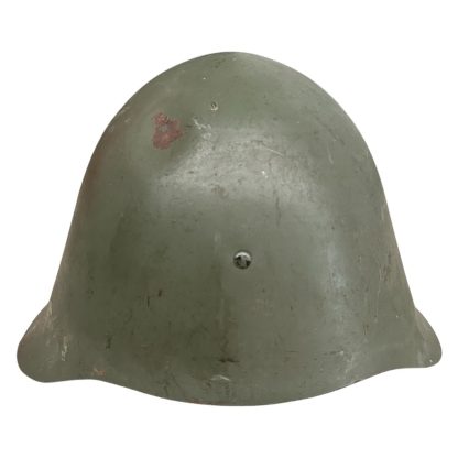 A WWII Danish M23/41 military helmet, featuring a rounded steel design with a green matte finish and a slightly flared brim. The helmet shows signs of wear, including scuffs and a small patch of exposed metal due to paint chipping. A single rivet is visible at the front for ventilation or securing the liner.