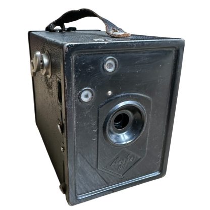 A vintage WWII-era German 'Agfa' box camera, featuring a black rectangular body with a textured surface, a metal handle on top, and a simple lens design. The camera has a minimalistic front panel with the Agfa logo embossed, indicative of its mid-20th century design. It is in used condition, with visible signs of wear on the leather strap and edges.