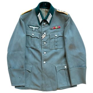 WWII German Wehrmacht M36 uniform jacket for a Hauptmann (Captain) of Kavallerie-Regiment 14, featuring green wool fabric with dark green collar, silver shoulder boards, breast eagle insignia, ribbon bar, and wiederholungsspange, preserved in historical condition.