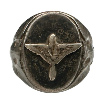 Antique silver ring from World War II, worn by a member of the United States Army Air Forces (USAAF). The ring features a prominent relief of a stylized aircraft on an oval front, with ornate details on the sides symbolizing aviation. The ring shows a weathered patina, highlighting its historical significance.