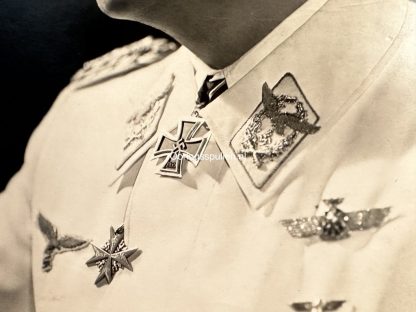 Black and white portrait photograph of Hermann Göring, a high-ranking Nazi official, wearing a white military uniform adorned with various medals and insignia. The photograph is taken from a side profile, showing his facial features in strong lighting. The watermark 'Oorlogsspullen.nl' is visible in the center of the image.