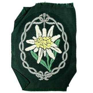 Original WWII German Wehrmacht Gebirgsjäger (Mountain Troops) arm insignia featuring an embroidered Edelweiss flower surrounded by a decorative border, symbolizing the elite mountain infantry.