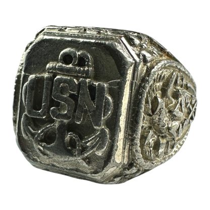 A vintage silver-tone United States Navy (USN) ring from World War II, featuring a raised emblem of an anchor with the letters 'USN' prominently displayed on the face. The ring has intricate engravings on the sides, showing detailed military-themed designs, and appears worn, indicating its historical significance.