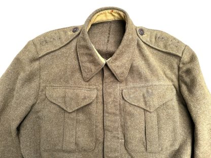 A vintage 1941 Canadian Battle Dress jacket in khaki wool, featuring two chest pockets with buttoned flaps, a fold-down collar, epaulets with buttons on the shoulders, and a belted waist. The jacket has a cropped fit, long sleeves with buttoned cuffs, and a partially visible beige lining. The fabric appears thick and durable, characteristic of World War II military uniforms.