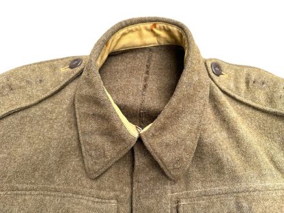 A vintage 1941 Canadian Battle Dress jacket in khaki wool, featuring two chest pockets with buttoned flaps, a fold-down collar, epaulets with buttons on the shoulders, and a belted waist. The jacket has a cropped fit, long sleeves with buttoned cuffs, and a partially visible beige lining. The fabric appears thick and durable, characteristic of World War II military uniforms.