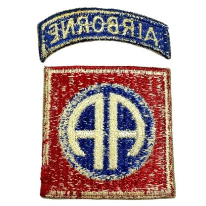 A World War II-era U.S. 82nd Airborne Division patch with a white back. The patch consists of a curved blue tab with 'AIRBORNE' embroidered in white thread, and a square red patch featuring a blue circle with a white 'AA' insignia in the center, representing the 'All American' nickname of the division.