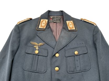 WWII German Luftwaffe General's tunic in blue-gray fabric, featuring gold buttons, gold-embroidered shoulder boards, a gold-braided breast eagle insignia on the right chest, and four front pockets with flaps.