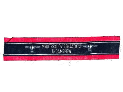 A WWII-era German Volkssturm armband, featuring a red and black design with white lettering reading 'DEUTSCHER VOLKSSTURM WEHRMACHT' and an eagle and swastika emblem. The fabric appears unissued, with frayed edges.