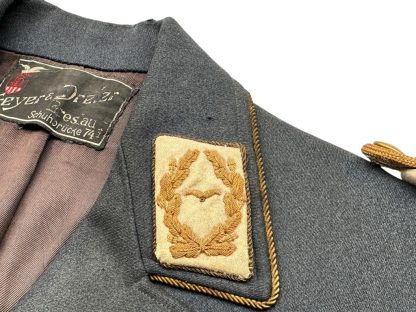 Close-up of a WWII German Luftwaffe General's tunic collar tab, featuring gold-embroidered oak leaves surrounding a Luftwaffe eagle on a beige background, bordered with gold braiding on a dark blue-gray wool base.